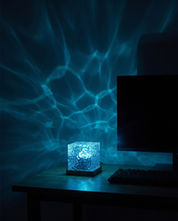 Square ripple lamp on a gaming desk throwing blue wave light on the wall